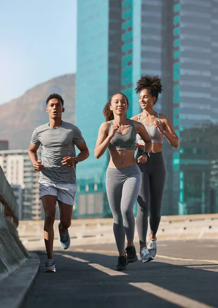 Diversity, fitness friends and running together in city for freedom or healthy lifestyle motivation. Runner athlete, sports training team and wellness coach outdoor workout for cardio exercise goal.