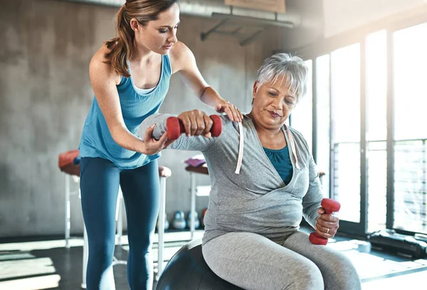Reversing muscle decline with the help of a physical therapist. a senior woman using weights and a fitness ball with the help of a physical therapist