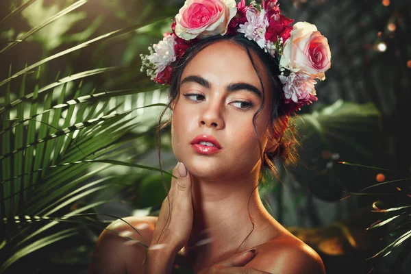 Flowers, nature and beauty of a model in a forest with natural skincare, makeup and skin wellness. Woman with a flower crown in a forest or jungle with organic skin care and natural cosmetics.
