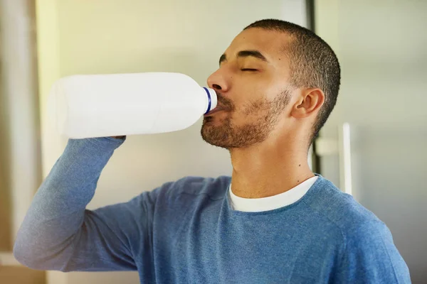 早上喝的第一口姆姆 一个年轻人在家里喝瓶子里的牛奶 — 图库照片