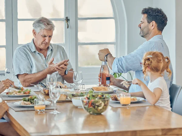 Lunch, dining room and family eating together in celebration at a modern home with food and champagne. Hurt grandfather in retirement, father and child enjoying a food meal at a dinner table at house.