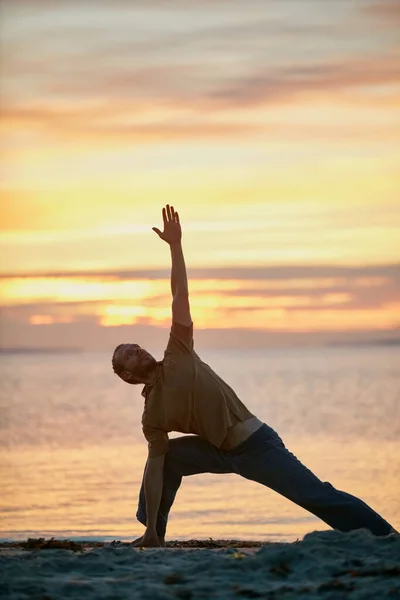 Yoga - bind the body and mind. a man practicing the triangle pose during his yoga routine at the beach