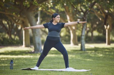 Yoga, esneme ve kilo verme, vücut sağlığı, fitness eğitimi ve doğa parkı alanında pilates eğitimi. Akıl sağlığı, sağlıklı yaşam tarzı ve spor yapan biri, dışarıda esneme hareketleri yapıyor..