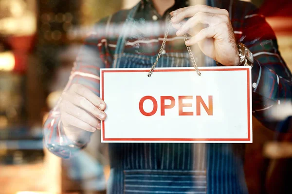 stock image Its opening day. Closeup shot of an unrecognizable man hanging up an open sign in a shop window