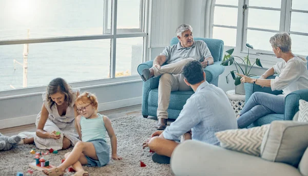 Family, generations and love together in living room with parents, grandparents and child play with toys and bonding. Big family, men with women and kid at home, spending quality time and care