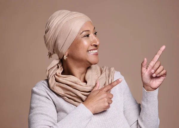 成熟したイスラム教徒の女性 ポインティングや広告モックアップ マーケティングスペースやスタジオの背景モックアップ プロモーション契約や製品の配置手のジェスチャーで幸せな笑顔 イスラム教徒のモデルやファッションヒジャーブスカーフ — ストック写真