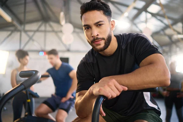 Gym, portrait and man exercise on spinning bike for health, training and fitness goal at a sports center. Personal trainer, coach and mexican man with a vision for wellness, heart health and workout.