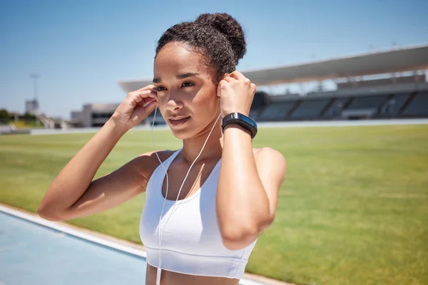 Fitness, music and exercise with a sports black woman listening to audio while track running or training. Workout, health and cardio with a female runner or athlete streaming the radio with earphones.