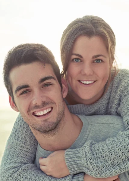 stock image Were so happy we found each other. Portrait of a happy young man giving his girlfriend a piggyback ride outside