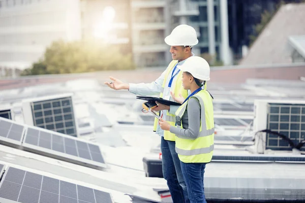 Engineering, solar panels and team planning a maintenance project outdoor in the city on a rooftop. Solar energy, eco friendly and industrial workers in collaboration working on photovoltaic cells