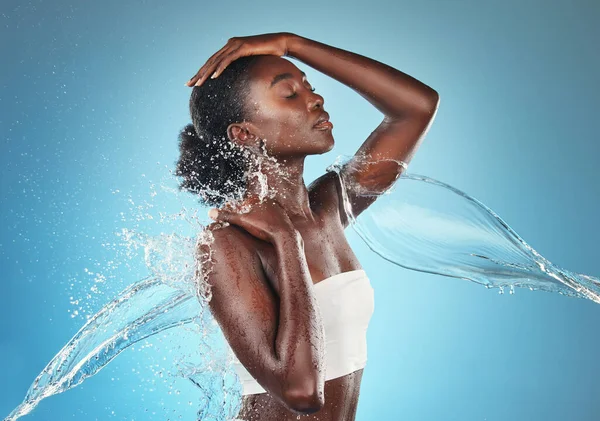 体にスプラッシュと水 洗浄と黒の女性は 健康と青のスタジオの背景に対する水分補給で気をつけます スキンケアと健康のための液体とシャワー 豪華さとアフリカモデル — ストック写真