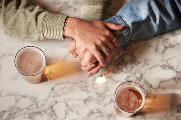 stock image Couple holding hands, above glass beer and bar with comfort, support or bonding together with drink. Helping hand, alcohol or trust with unity, love or care on countertop for empathy communication.