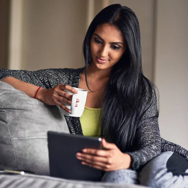 Comfortable at home, connected to the world. an attractive young woman surfing the net while sitting on her sofa at home