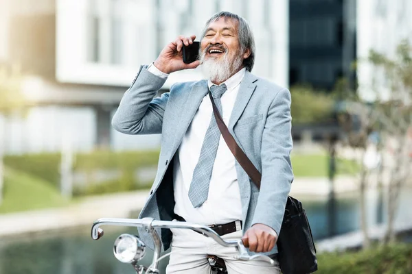 Stock image Phone call, businessman and cycling asian man on a trip or journey to work in the city during the day. Cycle, bike and bicycle with male businessperson on cellphone communication during urban commute.