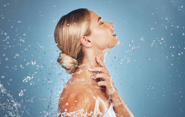 Skincare, water and profile of woman on blue background in studio for beauty, facial and wellness. Hydration, skincare products and girl model for washing, cleaning and body cleanse at luxury spa.