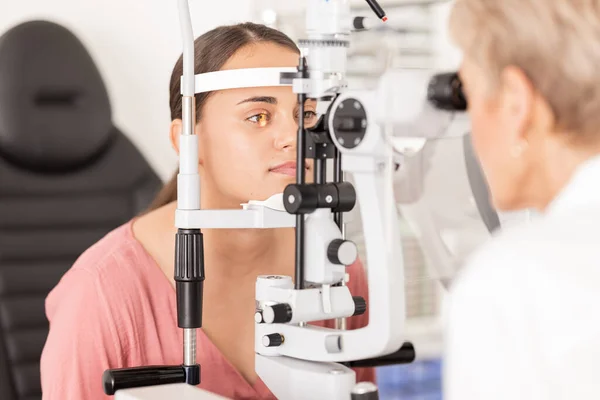 Eye, optometrist and eye exam in ophthalmologist office with optical machine to examine vision weak iris, pupil or lens of eyeball. Woman, optical clinic test and professional optician eye care test.