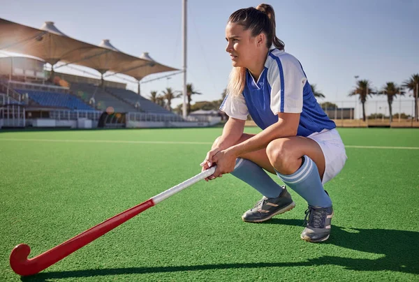 Sports, hockey and woman relax on field during match, thinking and planning a game strategy. Field hockey, coach and girl with stick, athletic and mindset at stadium for training, exercise and sport.
