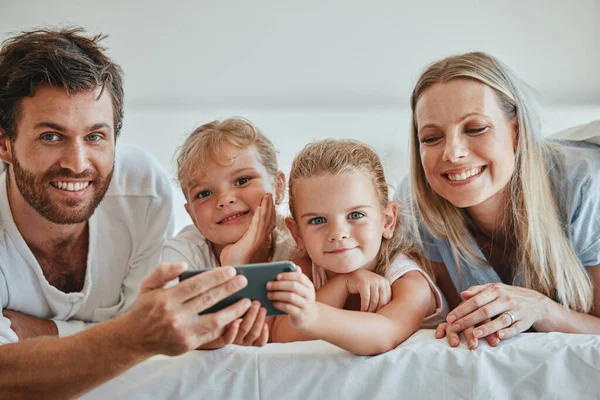 家庭和放松与手机在床上快乐的娱乐流连忘返在家里 爸爸和孩子们在卧室里放松一下 笑着在屋里用智能手机观看网上节目 — 图库照片