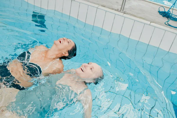 Swimming pool, fitness and physiotherapy with senior women for training, wellness and sports exercise. Relax, peace and workout with elderly friends in water for health, retirement and rehabilitation.