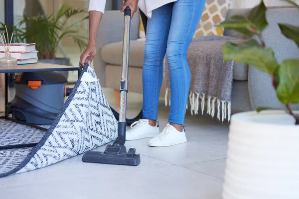 Cleaning, carpet and vacuum with black woman in living room for dust, furniture or housekeeping service. Electric, dirt and cleaner with shoes of housewife and floor at home for hygiene and lifestyle.