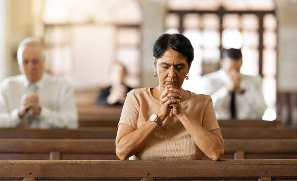 Faith, woman and praying in church, religion and spiritual connect, communication or believe. Senior female, mature lady or prayer in chapel with congregation, worship or trust with gratitude or hope.