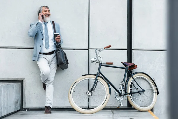 Bicycle, phone call and business man in city for communication, networking and carbon footprint travel marketing update with smile. Happy, healthy senior corporate manager coffee, bike and cellphone.
