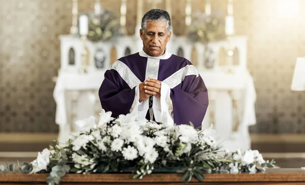 Funeral, prayer and pastor in a church for worship, farewell and praying over a coffin. Pray, death and church service by a priest talking, offering comfort and spiritual guidance at funeral service.