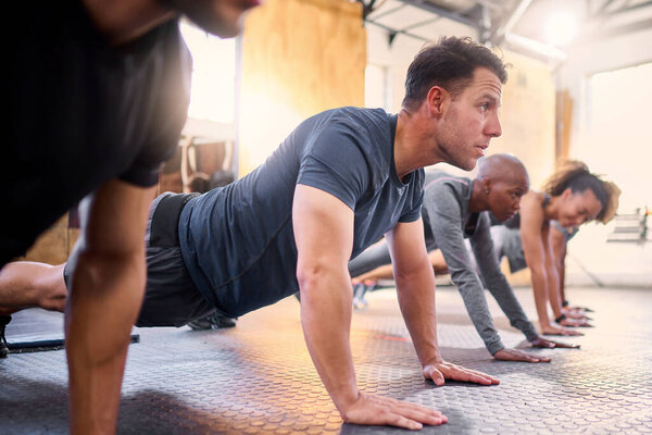Wellness, team and push ups in gym, workout and fitness for focus, training together and health. Group, diversity or athletic people in sportswear being healthy, strong or with endurance for exercise.