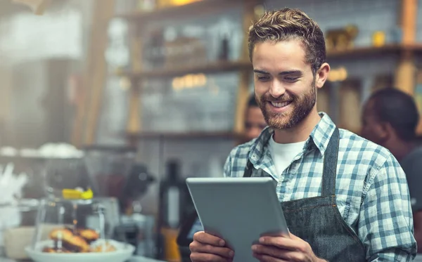 Stock image Staying on top of small business trends with modern technology. a young man using a digital tablet in the store that he works at