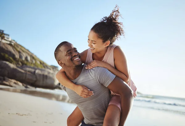 ピギーバックと黒のカップルビーチを歩くと 笑顔と一緒に幸せ 結合と屋外のために ロマンチックで男は女性を運ぶか 関係のための海辺の休暇 休日やロマンスに愛情 — ストック写真