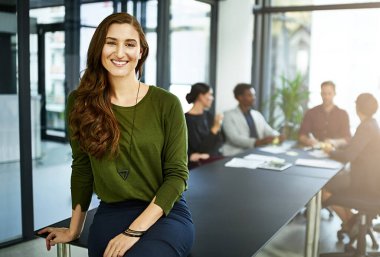 It takes a great leader to build a business. Portrait of a businesswoman in a boardroom with her colleagues blurred out in the background clipart