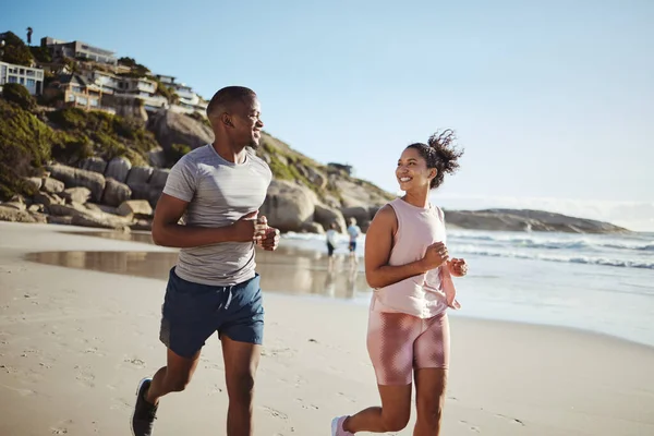 Couple, fitness and running with smile at the beach, exercise and cardio, happiness and active lifestyle. Young, happy people, runner and health, body training and motivation workout outdoor at ocean.