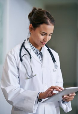 Sağlığın hakkında bilgilendirici kararlar veriyorsun. İş yerinde dijital tablet kullanan genç bir doktor.