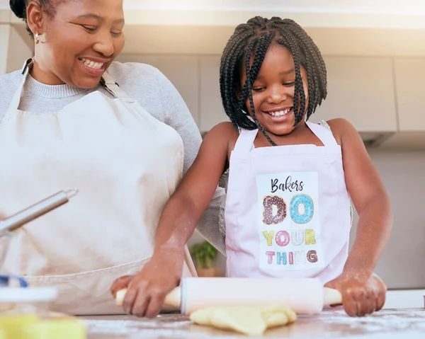 Black woman, girl or bonding and baking in kitchen of house or family home with help, support or learning education with mom. Smile, happy and cooking child with mother and pastry for food or dessert.