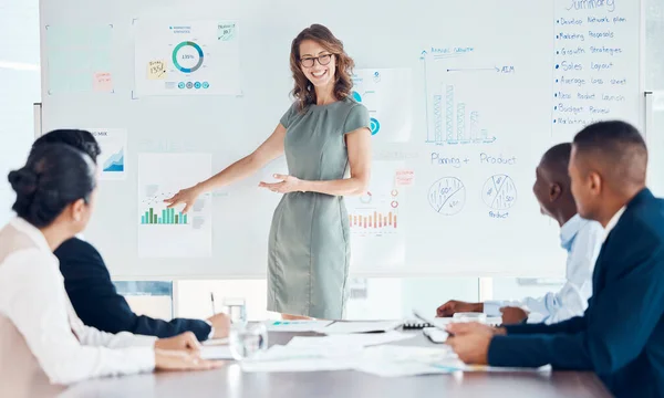 Business woman, leadership and coaching on whiteboard for marketing strategy, meeting or presentation at the office. Happy female manager or mentor teaching employee workers company graph analytics.