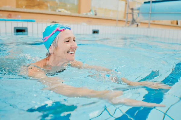 Swimming, physiotherapy and exercise with a senior woman in water for rehabilitation or recovery. Fitness, pool and health with a mature female being active during a swim in the gym for wellness.