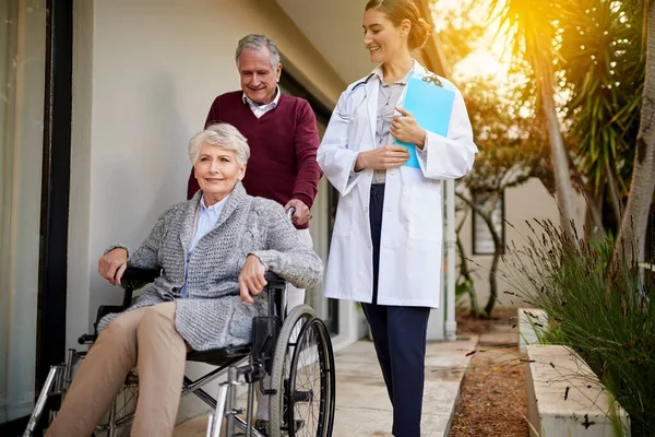 只有最好的护理对她的病人来说才够好 一对老年夫妇和一个疗养院外的护士 — 图库照片