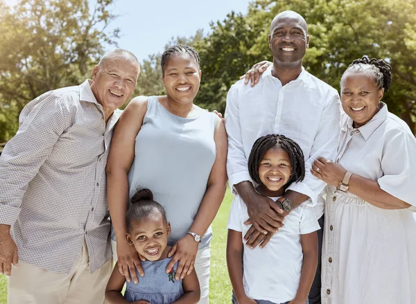 Portrait of happy black family with smile in park, garden or outdoor picnic venue. Men, women and kids together on grass at family event and making memories, generations with girl children and couple.