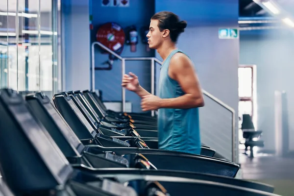 Treadmill, running and profile of man in gym for cardio workout and heart health. Fitness, sports and male runner on machine practicing for marathon, race or training for wellness in fitness center