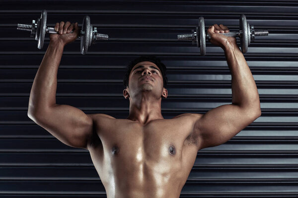 Lift it. a handsome young man working out with dumbbells