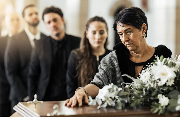 Funeral, death and coffin in church or Christian family gathering together for support. Religion, sad people and mourning loss or religious catholic men and women grief in church service over casket.