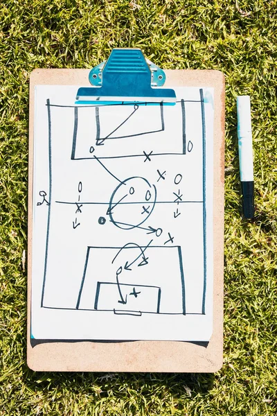 Sports, soccer field and clipboard planning a strategy for a group mission, target or tactics for goals. Solutions, teamwork and coach drawing winning tactics or ideas on grass in a football stadium.