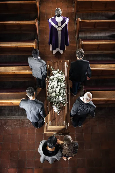 Funeral, church and sad people carrying coffin with a priest, pallbearers and church pew from above, death, mourning and day of remembrance. Church service, casket and grieving family and friends.
