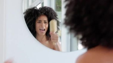 Siyah kadın, banyoda aynanın karşısında dans edip şarkı söylüyor, eğleniyor ve güne hazırlanıyor. Saç bakımı, dans ya da sabah rutini. Güney Afrikalı, kıvırcık saçlı, saçlarına dokunan mutlu bir kadın..