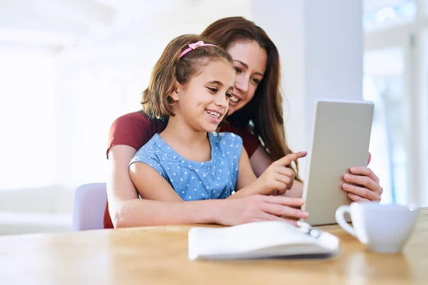 Learning through the digital age. mother and daughter using a digital tablet together at home