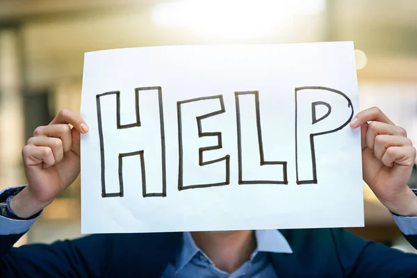 Everyone needs a bit of help. a businessman holding up a sign asking for help