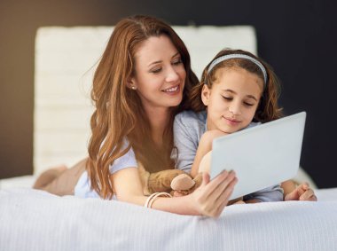 Birden fazla şekilde bağlanmak. Dijital tablet kullanan bir anne ve kızının tam boy görüntüsü.
