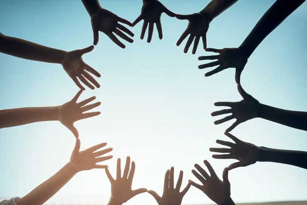 stock image Lets stand united as one. Low angle shot of a group of unidentifiable people forming a circle with their hands against a bright blue sky