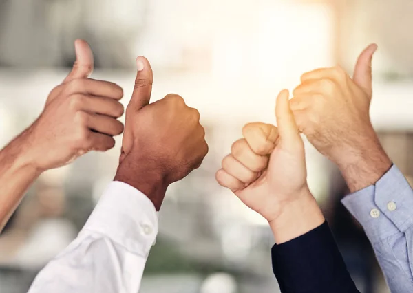 We couldnt agree more. Closeup shot of a group of unidentifiable businesspeople showing thumbs up in an office