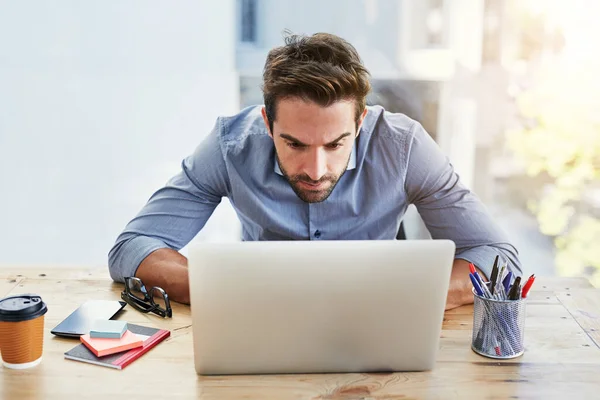 現代の技術はあなたのビジネスのための信じられないほどの事をする 彼のオフィスのノートパソコンの後ろに座っていたハンサムな若いビジネスマンは — ストック写真